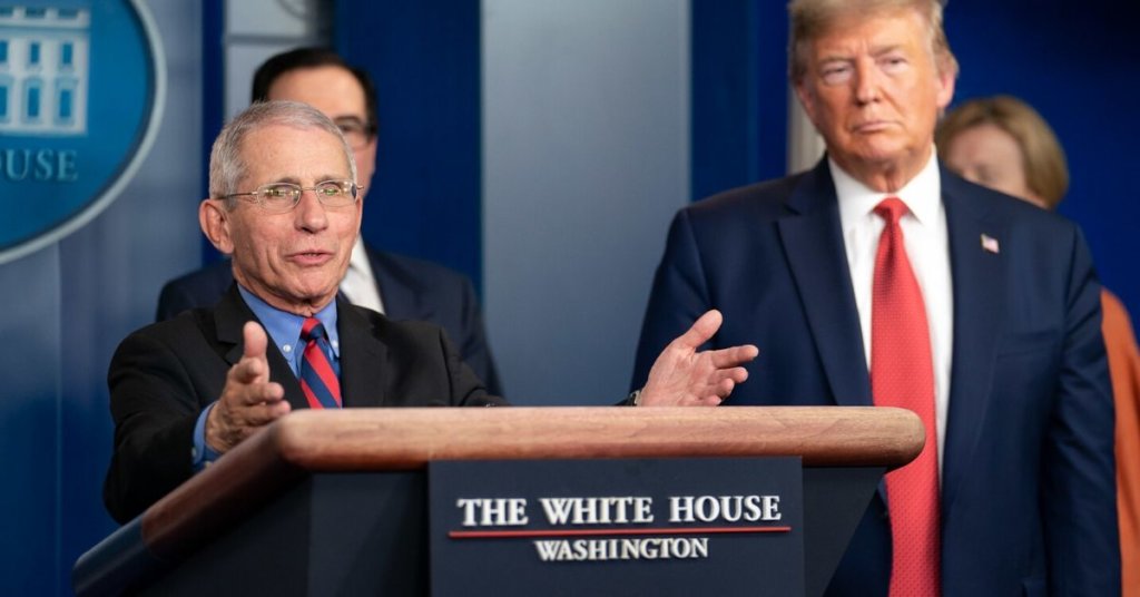 Dr. Fauci standing behind a podium with Trump looking on