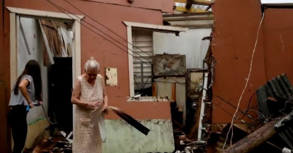 Woman next to her damaged home 