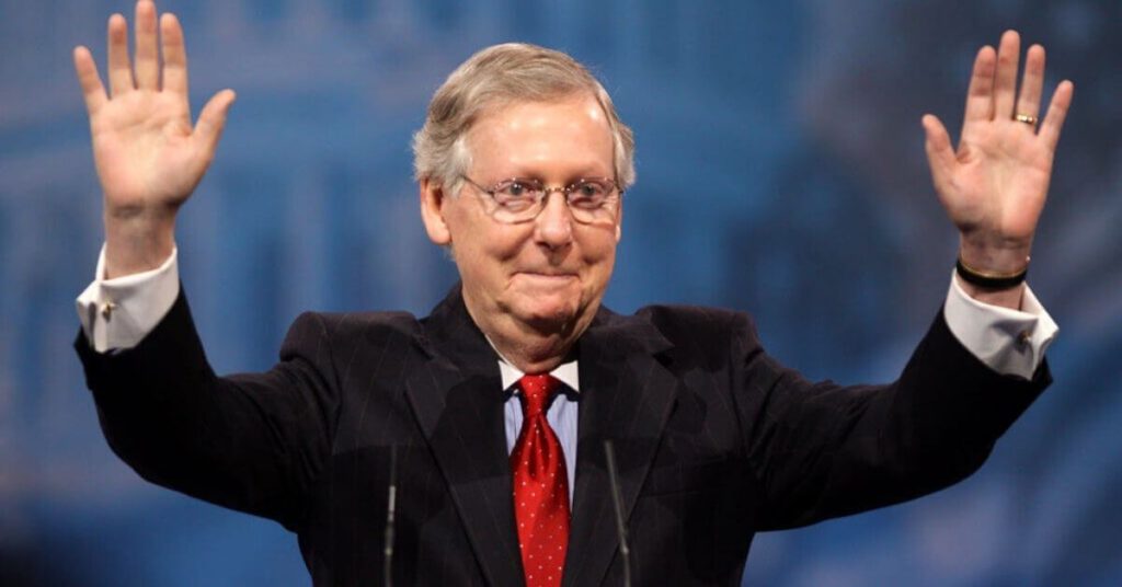 Mitch McConnell with his hands in the air