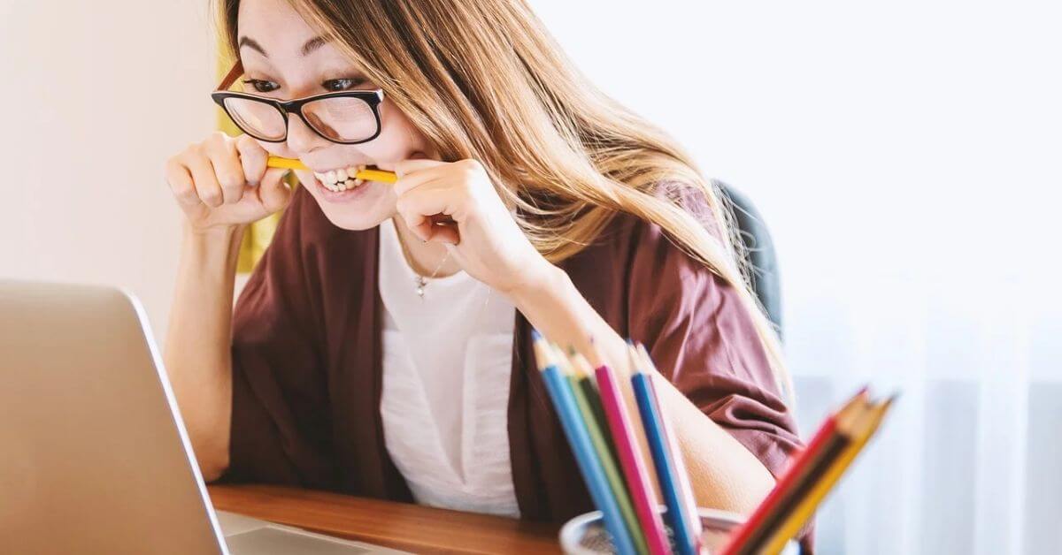 Women looking at a laptop biting a pencil