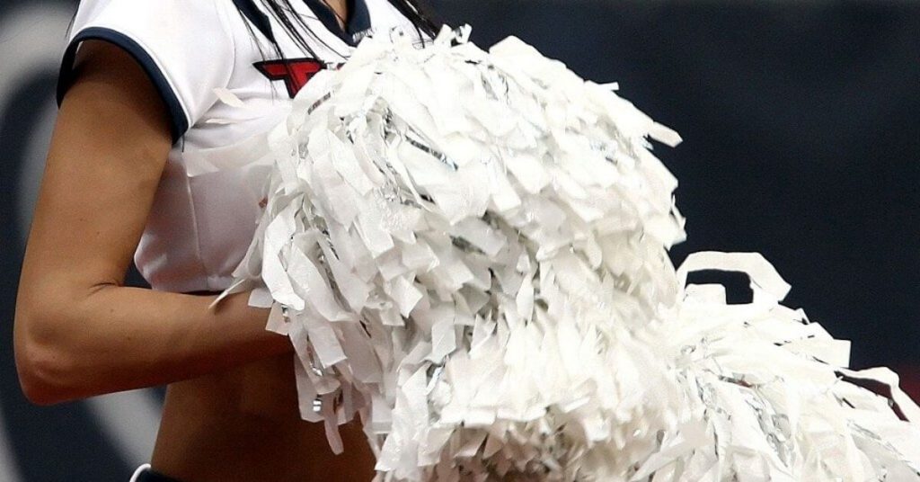 Cheerleader holding white pom pons