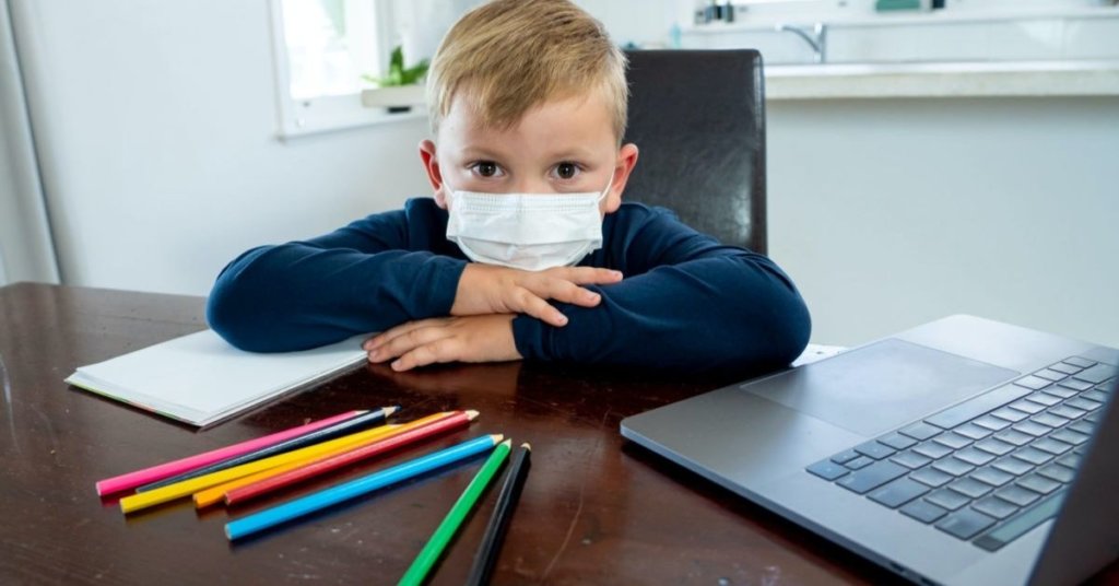 Child at a table wearing a facemask