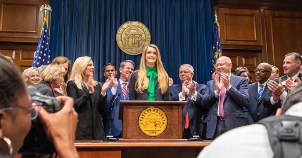 Kelly Loeffler standing at a podium with several other lawmakers behind her