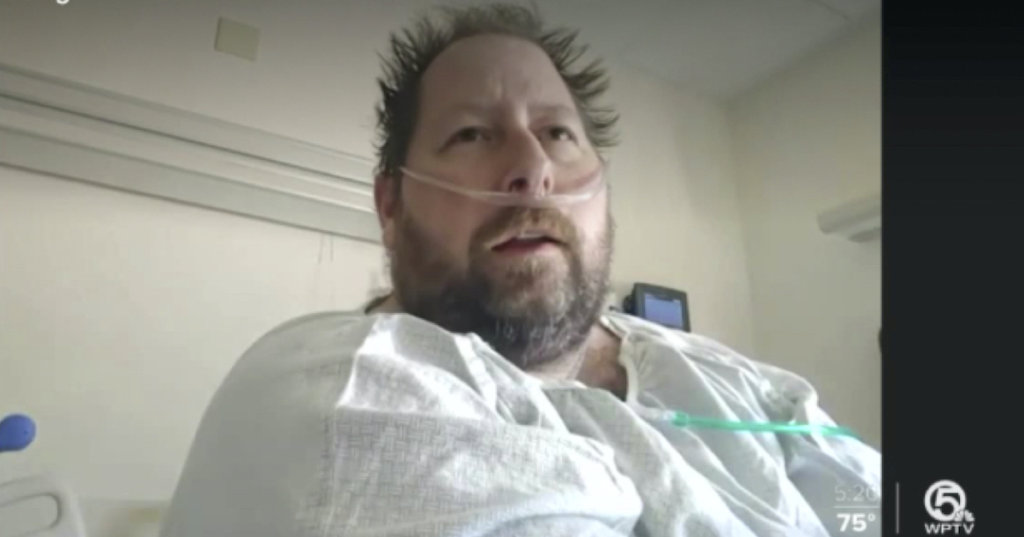 A photograph of a man sitting in a hospital gown.