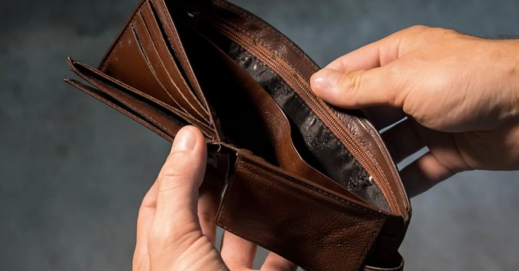 A person holding open an empty wallet