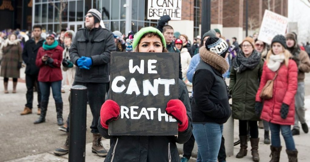 Woman at a BLM protest holding a sign that says "We can't breath"