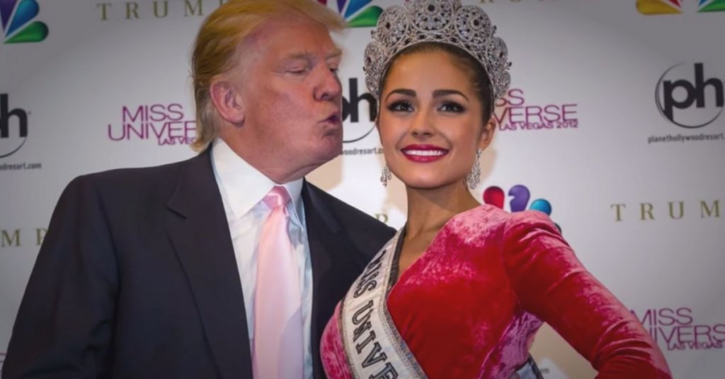 A photograph of Donald Trump leaning his puckered lips toward a beauty pageant contestant during a photo shoot.