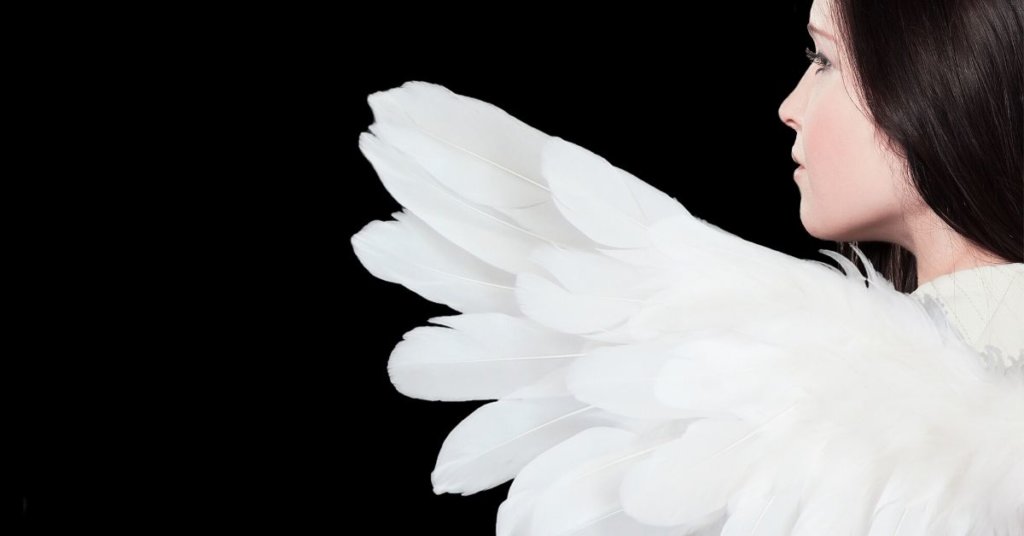 Woman dressed as an angel standing in front of a black background