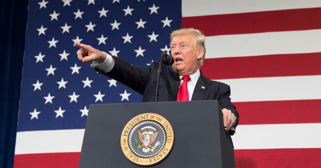 Trump standing at a podium pointing at the crowd