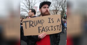 Man holding a sign that says "Trump is a fascist!"