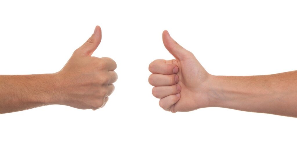 Two white hands give the thumbs up to each other