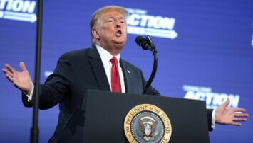 Trump with his arms out behind a podium