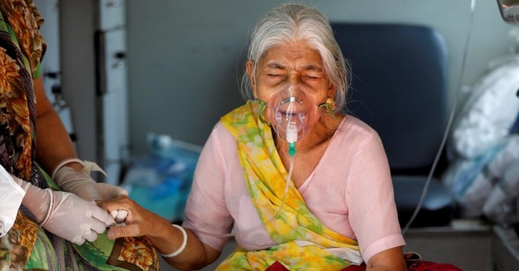Lilaben Gautambhai Modi, 80, wearing an oxygen mask, sits inside an ambulance as she waits to enter a COVID-19 hospital for treatment