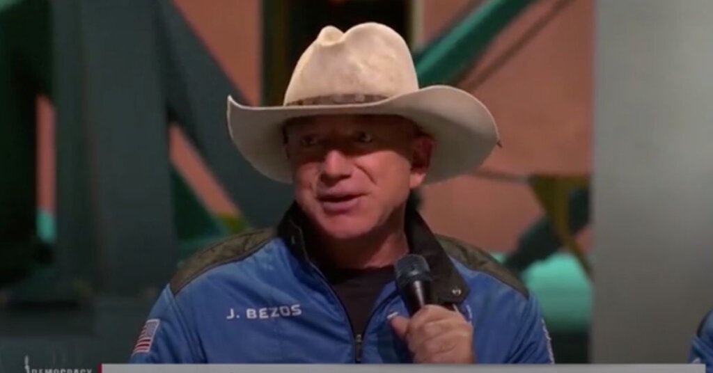 Jeff Bezos in a cowboy hat holding a microphone