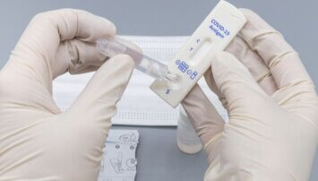 Close up of two hands doing a COVID antigen test